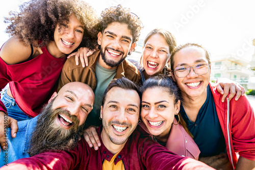 Multi cultural guys and girls taking genuine selfie outside - Happy diversity life style concept on young multiracial best friends having fun day together at summer location - Warm backlight filter