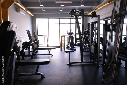  Sports equipment in the gym. Stylish bright sports space. Expanders and simulators with heavy dumbbells. Bench press, sport for a strong body and weight loss