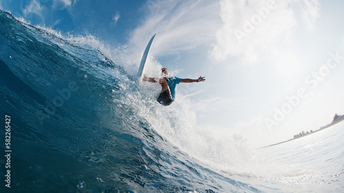 Pro surfer rides the wave. Young man surfs the ocean wave in the Maldives and aggressively turns on the lip. Splitted above and underwater view