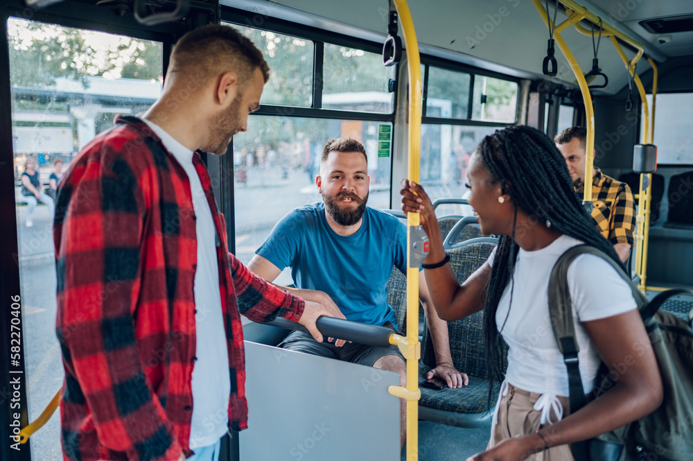 Multiracial friends talking while riding a bus in the city Multiracial friends talking while riding a bus in the city