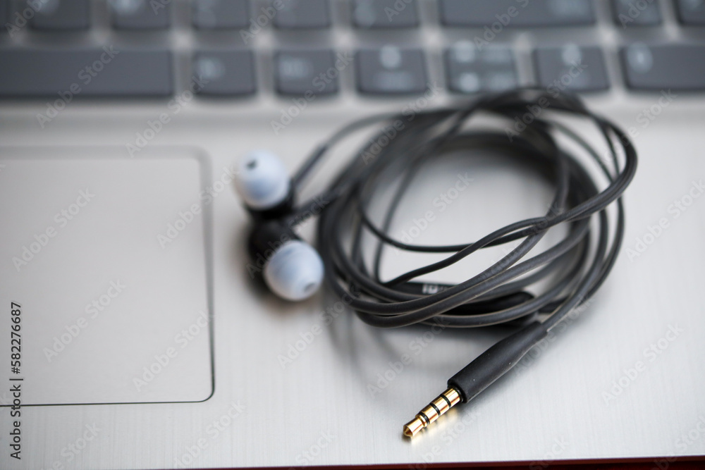 Black earphone, close up photo, on the laptop keyboard Black earphone, close up photo, on the laptop keyboard