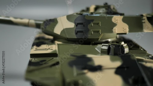 Close-up shot of an isolated radio-controlled toy tank that drives, rotates the turret and fires from the muzzle. Military children's toys. A game of war games with heavy weapons. RC toy tank