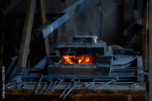 The fire of a blacksmith's forge in a brick kiln. Blacksmith tools lying next to the blacksmith's furnace.