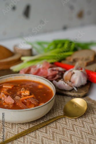 The traditional Ukrainian first course is red borsch. Hot borsch on the table with garlic, pepper, salt, onions and Ukrainian rye bread. Recipe for borsch with vegetables