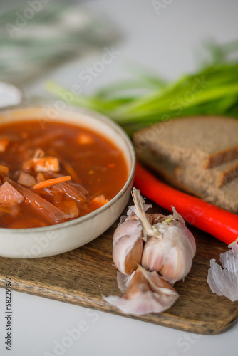 The traditional Ukrainian first course is red borsch. Hot borsch on the table with garlic, pepper, salt, onions and Ukrainian rye bread. Recipe for borsch with vegetables