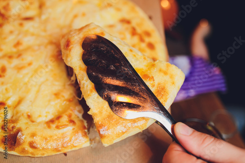 Azerbaijani restaurant dish with vegetable decor on a wooden background. Khachapuri in Megrelian on the Board. photo