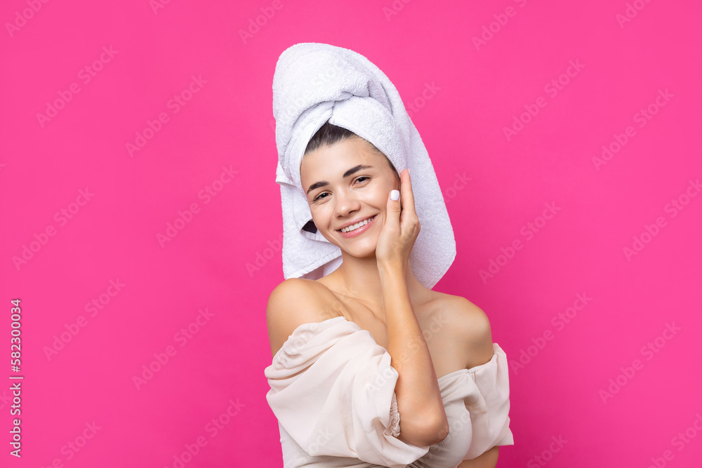 Portrait of young beautiful woman after bath. Beauty face of a cheerful attractive girl with towel on head against a pink background. Portrait of young beautiful woman after bath. Beauty face of a cheerful attractive girl with towel on head against a pink background.