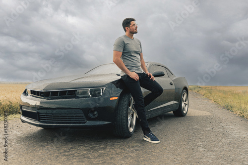sexy man and black sports car. Handsome guy traveling by his car.  Sportive man. guys love toys
