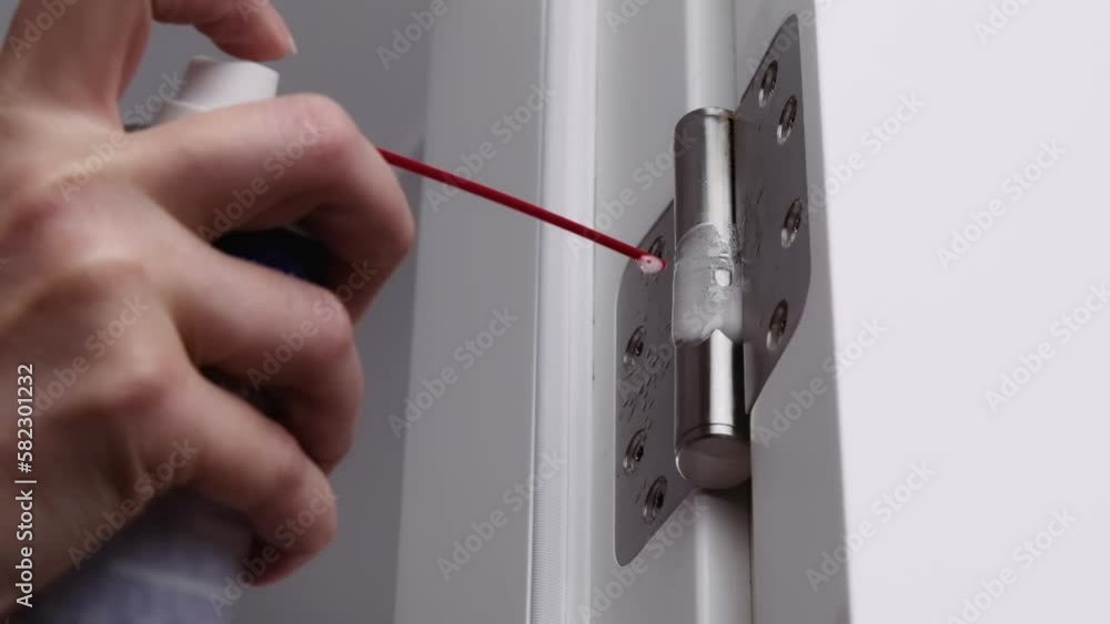 Stockvideo lubrication of door hinges. adjusting door hinge using lubricating oil. indoors