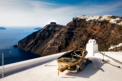 Wreck of a Row-Boat on the Roof of a Building on the Way between Imerovigli and Thera on Beautiful Santorini, Greece, with the Skaros Rock in the Background photo