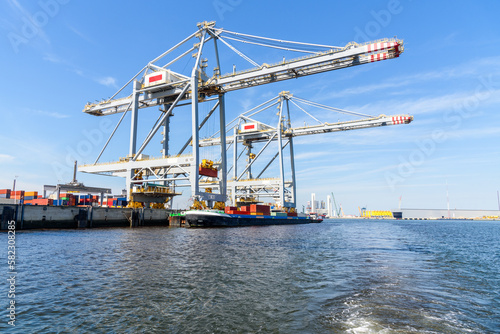 Cargo barge being loaded with containers in a port on a sunny summer day