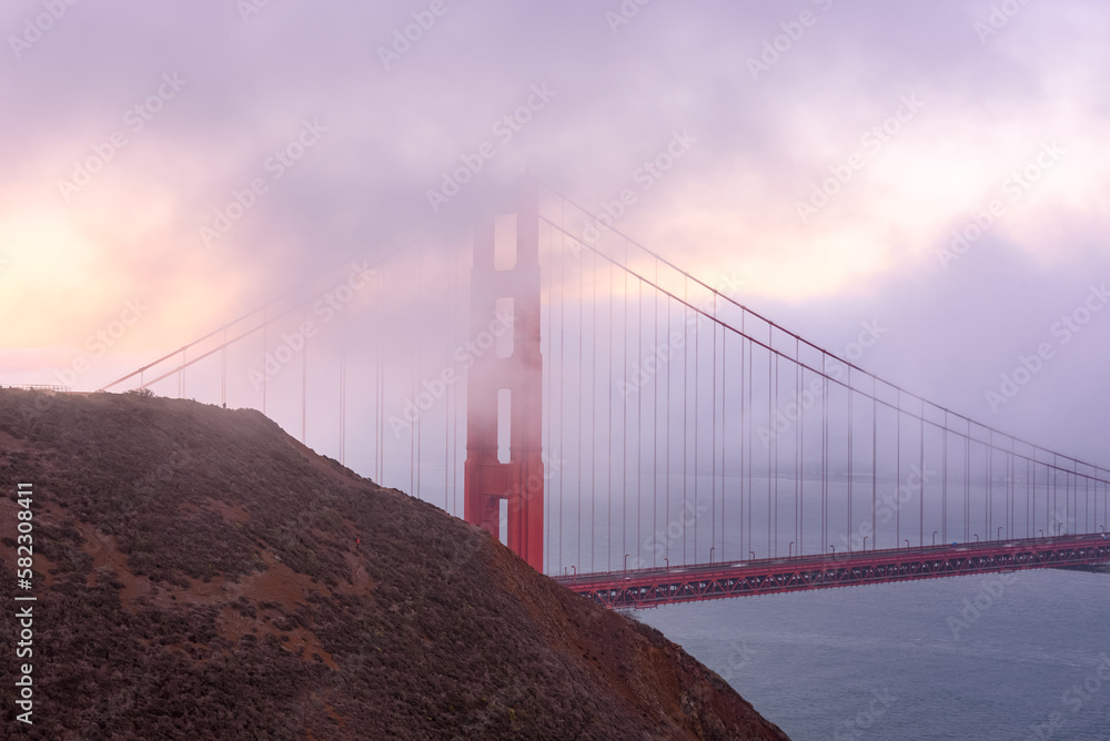 Fototapeta premium Goldeng Gate bridge shrouded in fog at sunset in autumn