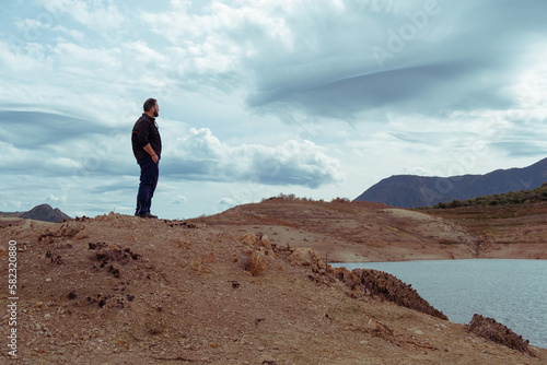 natural young man looking at the horizon on the mountain under a sky full of clouds