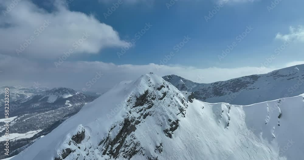 Aerial, drone shot over leafless trees, above a snowy mountain and beautiful snowy mountain peaks. Winter wilderness, on a sunny day. Aerial, drone shot over leafless trees, above a snowy mountain and beautiful snowy mountain peaks. Winter wilderness, on a sunny day.