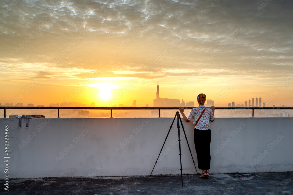 A woman watches the sunrise on the rooftop of a high-rise apartment building in Ho Chi Minh City, Vietnam.
