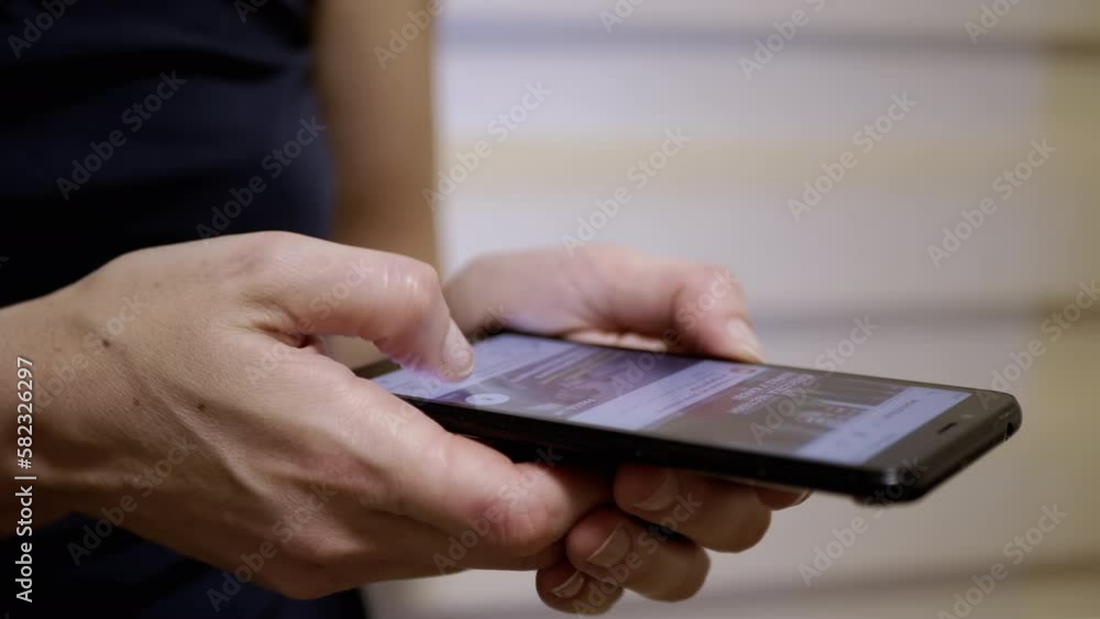 Female Fingers Scroll through the News Feed in Social Networks on a Mobile Phone. Close-up. Woman quickly browsing mobile applications on a smartphone. Fingers touch the screen. Life in a smartphone. Female Fingers Scroll through the News Feed in Social Networks on a Mobile Phone. Close-up. Woman quickly browsing mobile applications on a smartphone. Fingers touch the screen. Life in a smartphone.