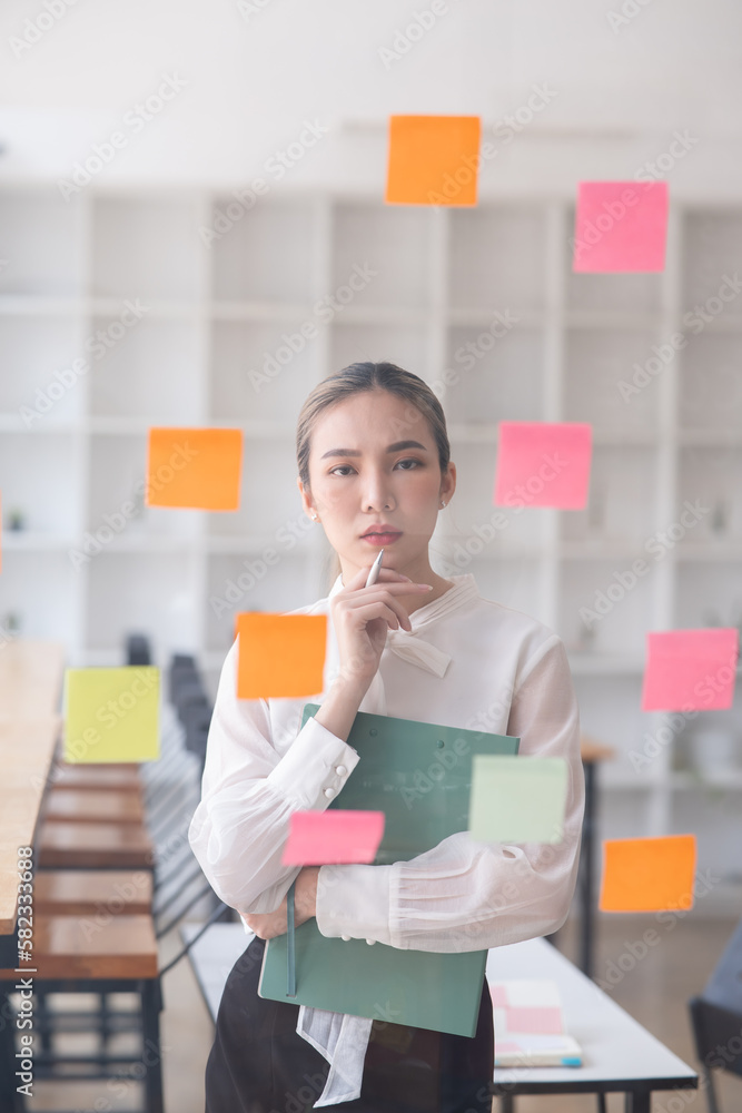 Young Asian businesswoman holding a note on the board presenting about financial business Young Asian businesswoman holding a note on the board presenting about financial business