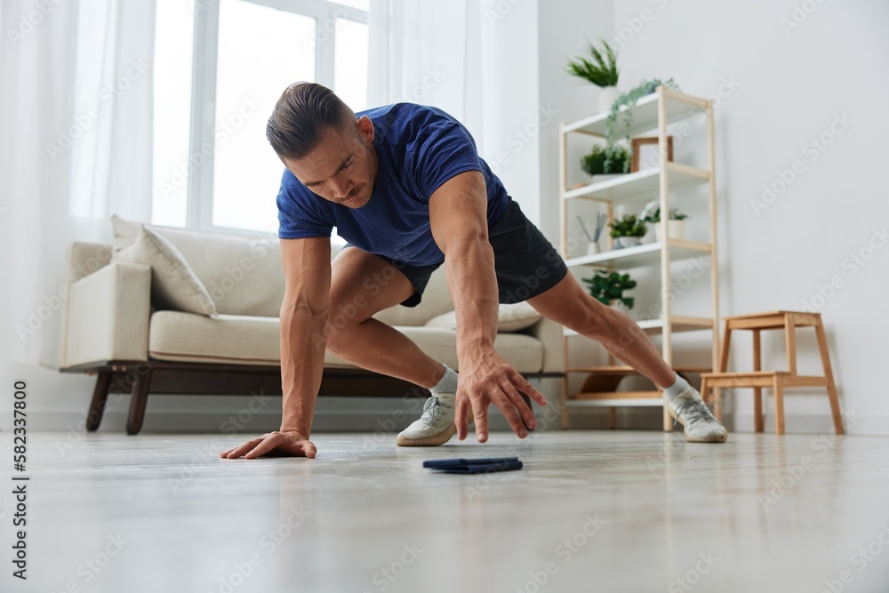 Man sportsman training at home, stretching exercises for arm, leg and back muscles, strong body and correct posture, the concept of health and beauty Man sportsman training at home, stretching exercises for arm, leg and back muscles, strong body and correct posture, the concept of health and beauty