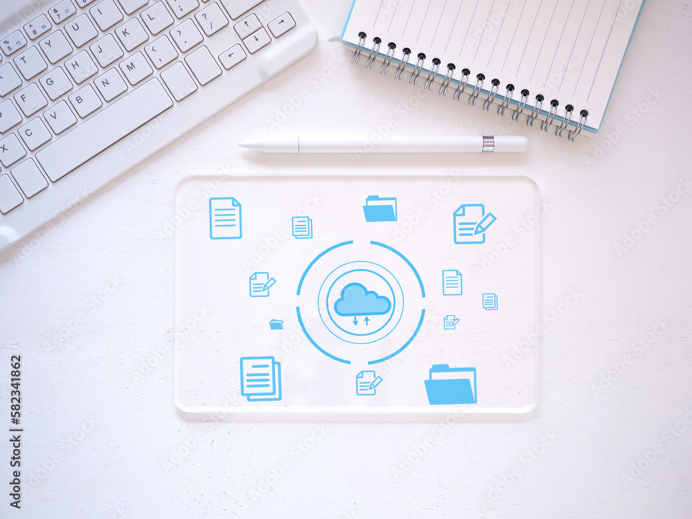 Transparent virtual tablet PC with icon document data technology and cloud computing and efficient online storage on white desk, keyboard, stylus pen, notebook. Top view, flat lay.. Transparent virtual tablet PC with icon document data technology and cloud computing and efficient online storage on white desk, keyboard, stylus pen, notebook. Top view, flat lay..