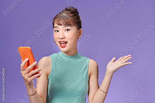 Happy asian woman feeling happiness and standing hold smartphone other hand open on purple background