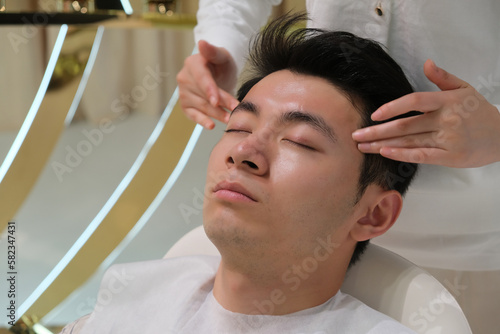 handsome Asian young man in head and face massage. facial massage, skincare and beauty treatment concept