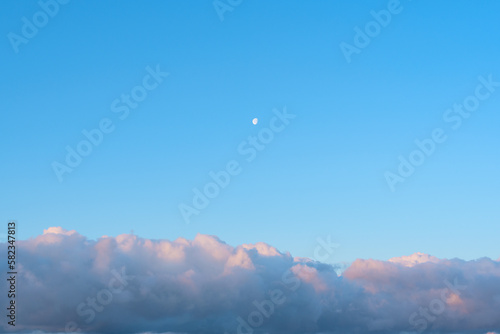 Bright blue sky with white fluffy clouds and the Moon. Beauty of nature. Aerial natural background