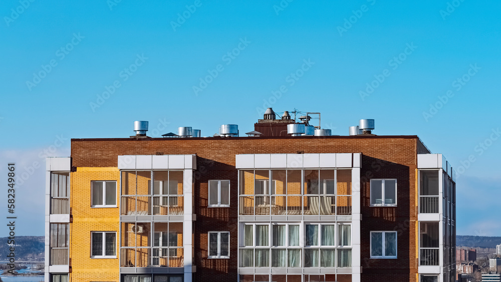 A modern house with a flat roof, air ducts and air conditioners above a modern apartment building. The concept of city development. Engineering systems