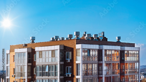 A modern house with a flat roof, air ducts and air conditioners above a modern apartment building. The concept of city development. Engineering systems