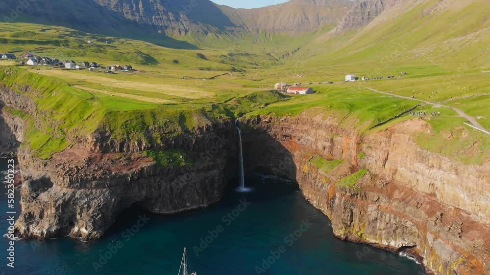 Gasadalur village and its iconic waterfall, Vagar, Faroe Islands, Denmark. Long exposure. (aerial photography) Gasadalur village and its iconic waterfall, Vagar, Faroe Islands, Denmark. Long exposure. (aerial photography)