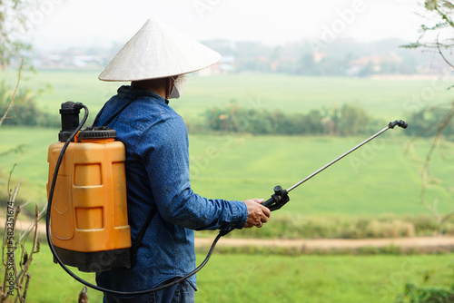 Asian farmer uses herbicides, insecticides chemical spray to get rid of weeds and insects or plant disease in the rice fields. Cause air pollution. Environmental , Agriculture chemicals concept.  © Sanhanat