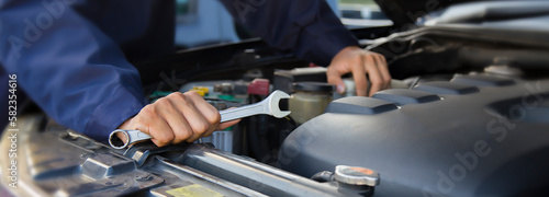 The mechanic works on the engine of the car in the garage, car repair service. 