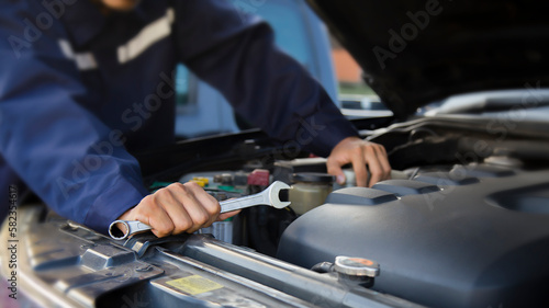 The mechanic works on the engine of the car in the garage, car repair service. 