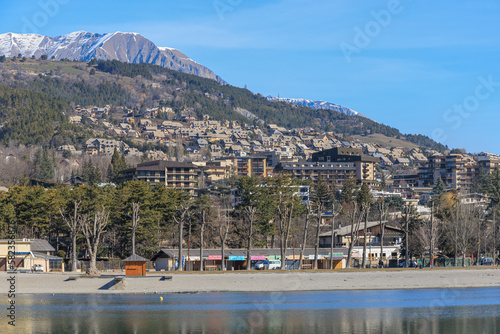 A scenics view of the Embrun, France lake with snowy mountains range in the background under a majestic blue sky photo