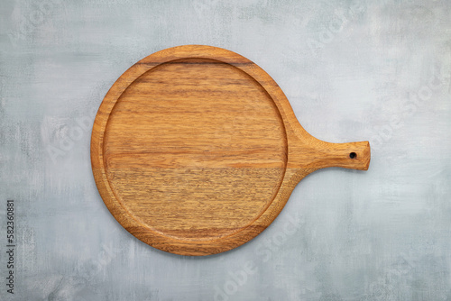Empty wooden pizza platter set up on grey concrete. Pizza tray on grey concrete background flat lay and copy space.