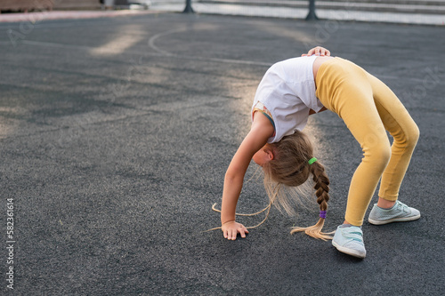 Caucasian girl doing bridge exercise on sports ground outdoors.  © Михаил Решетников
