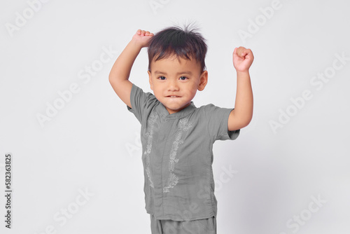Excited toddler Asian muslim boy standing with celebration victory isolated on white studio background