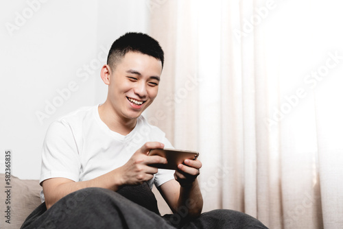Asian man is using mobile phone in the bed.