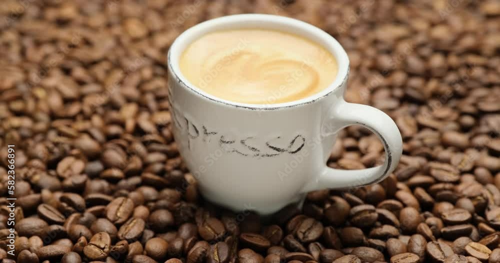 Ceramic cup of hot black coffee with a rotating background of fresh roasted coffee beans Ceramic cup of hot black coffee with a rotating background of fresh roasted coffee beans
