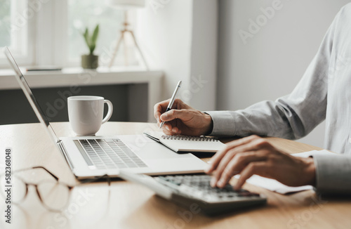 Man accountant using calculator and laptop computer in office, finance and accounting concept
