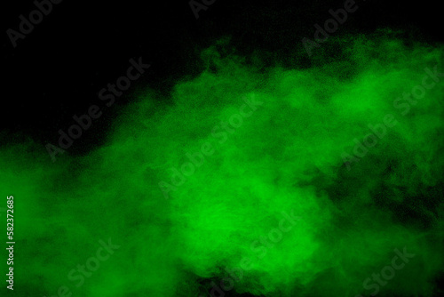 Abstract green powder explosion on black background.Freeze motion of green dust cloud.