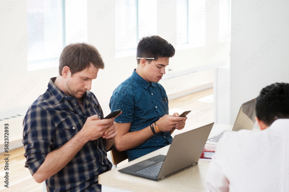 Businessmen using smart phones at desk in creative office Businessmen using smart phones at desk in creative office
