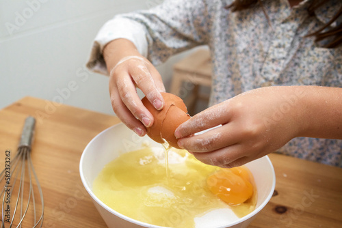 Cropped image of girl breaking eggs in bowl at table photo