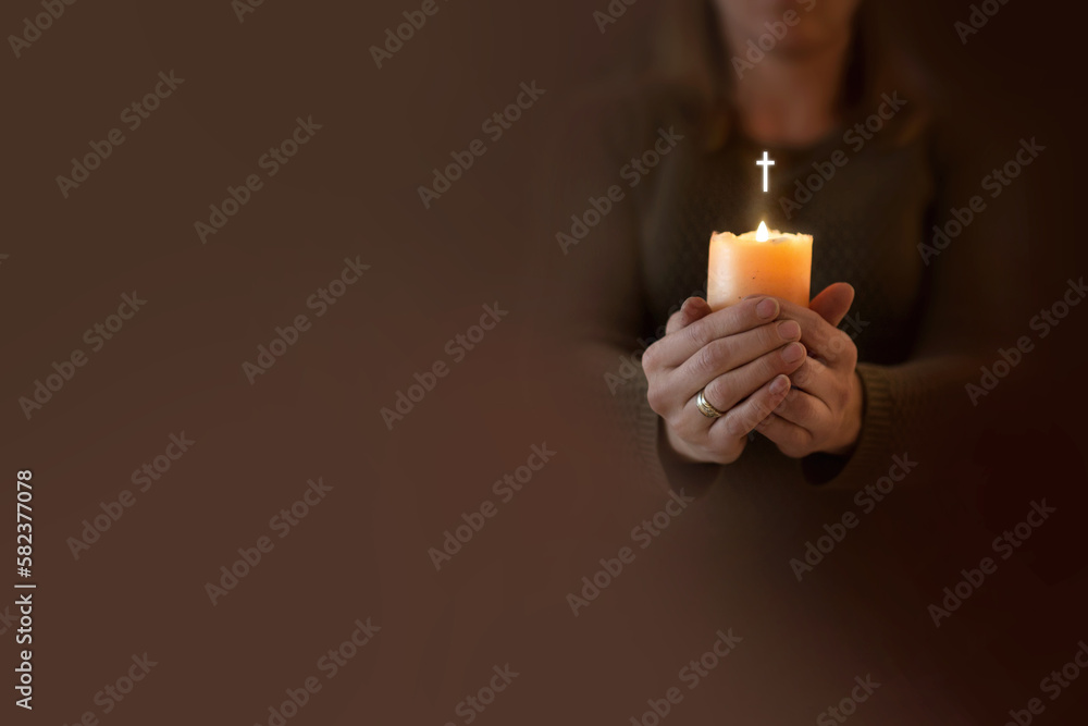 Kobieta modli się trzymając w dłoniach zapaloną świecę. Zmartwychwstanie pańskie wiara i nadzieja w modlitwie - obrazy, fototapety, plakaty 
