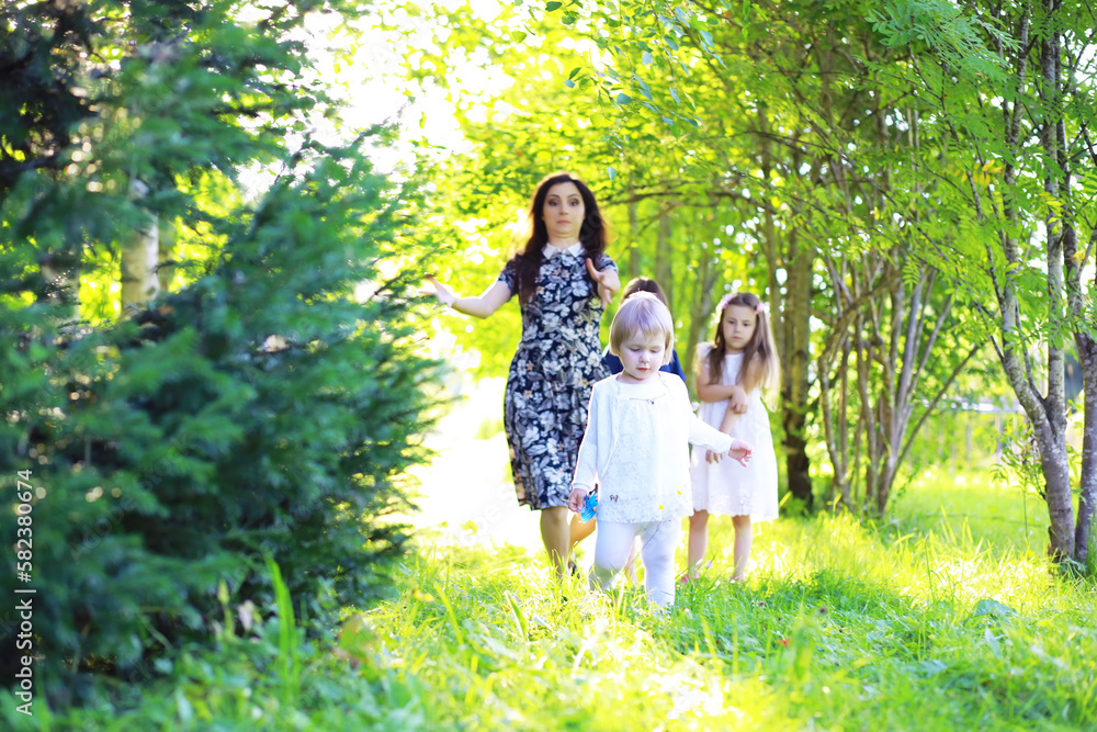 Young large family on a summer morning walk. Beautiful mother with children is playing in the park. Young large family on a summer morning walk. Beautiful mother with children is playing in the park.