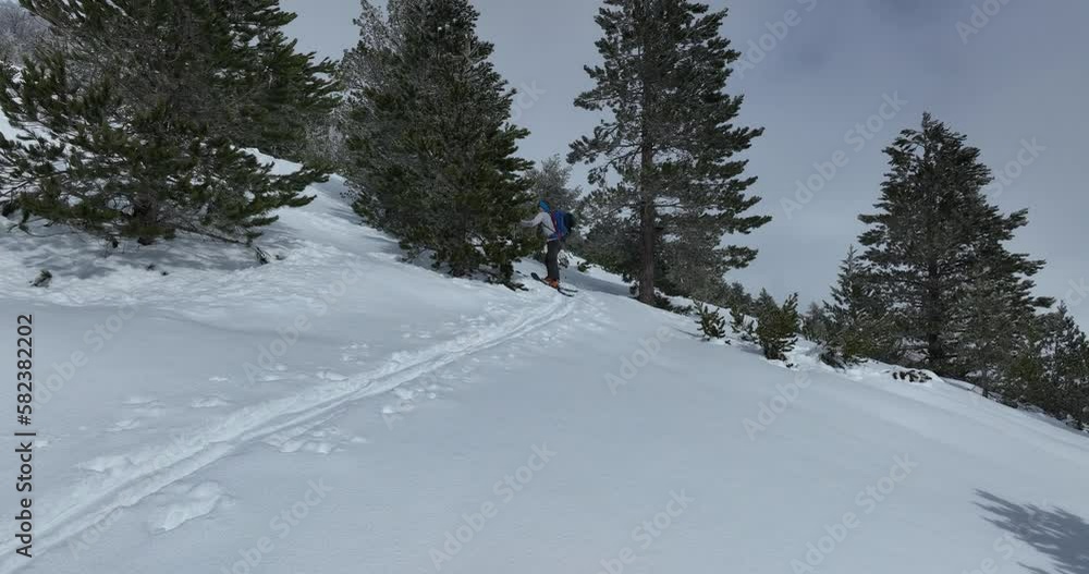 Aerial Ski touring man crossing over the camera view in the mountains in winter season fresh snow. Ski touring on skin uphill in a line. Powder day. ski vacation travel concept. Aerial Ski touring man crossing over the camera view in the mountains in winter season fresh snow. Ski touring on skin uphill in a line. Powder day. ski vacation travel concept.