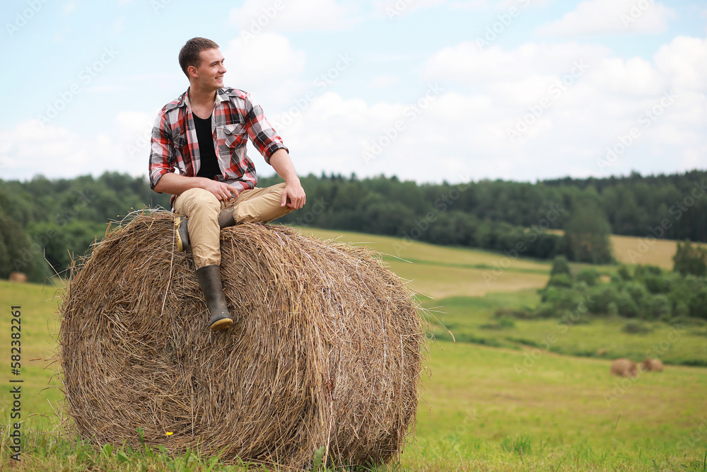 Young man in boots in a village field at sunset. Young man in boots in a village field at sunset.