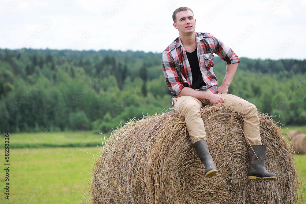 Young man in boots in a village field at sunset. Young man in boots in a village field at sunset.