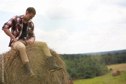 Young man in boots in a village field at sunset.
