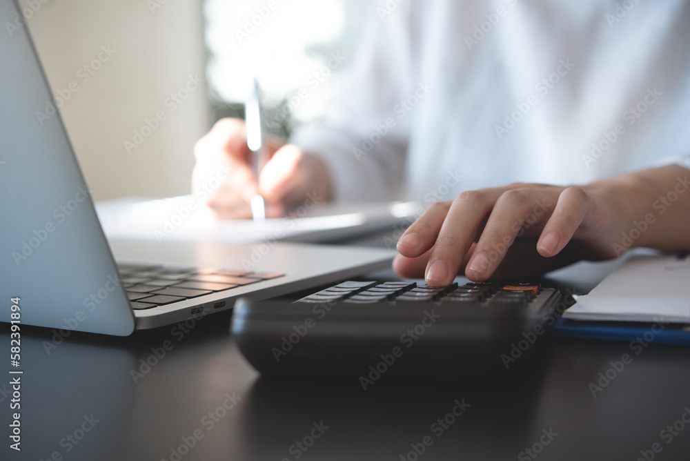 Close up of business woman accountant hand using calculator and laptop computer for calculating finance on desk office. business financial accounting concept - obrazy, fototapety, plakaty 
