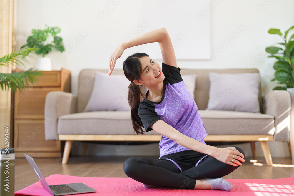 Sporty woman watching yoga training online and raise arm to stretching exercise for yoga at home Sporty woman watching yoga training online and raise arm to stretching exercise for yoga at home